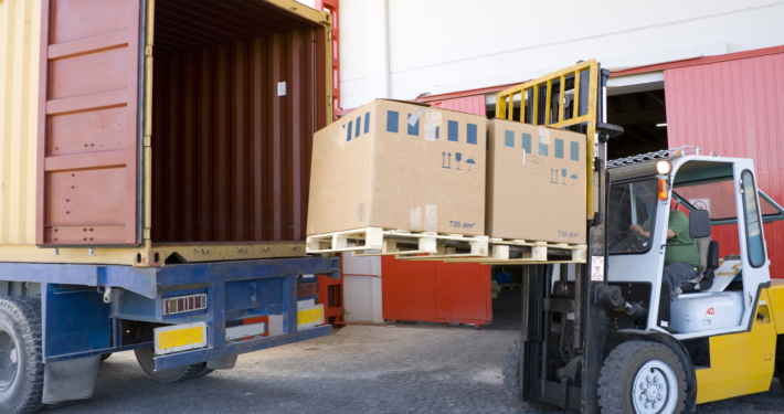 Forklift loading two pallets onto a truck