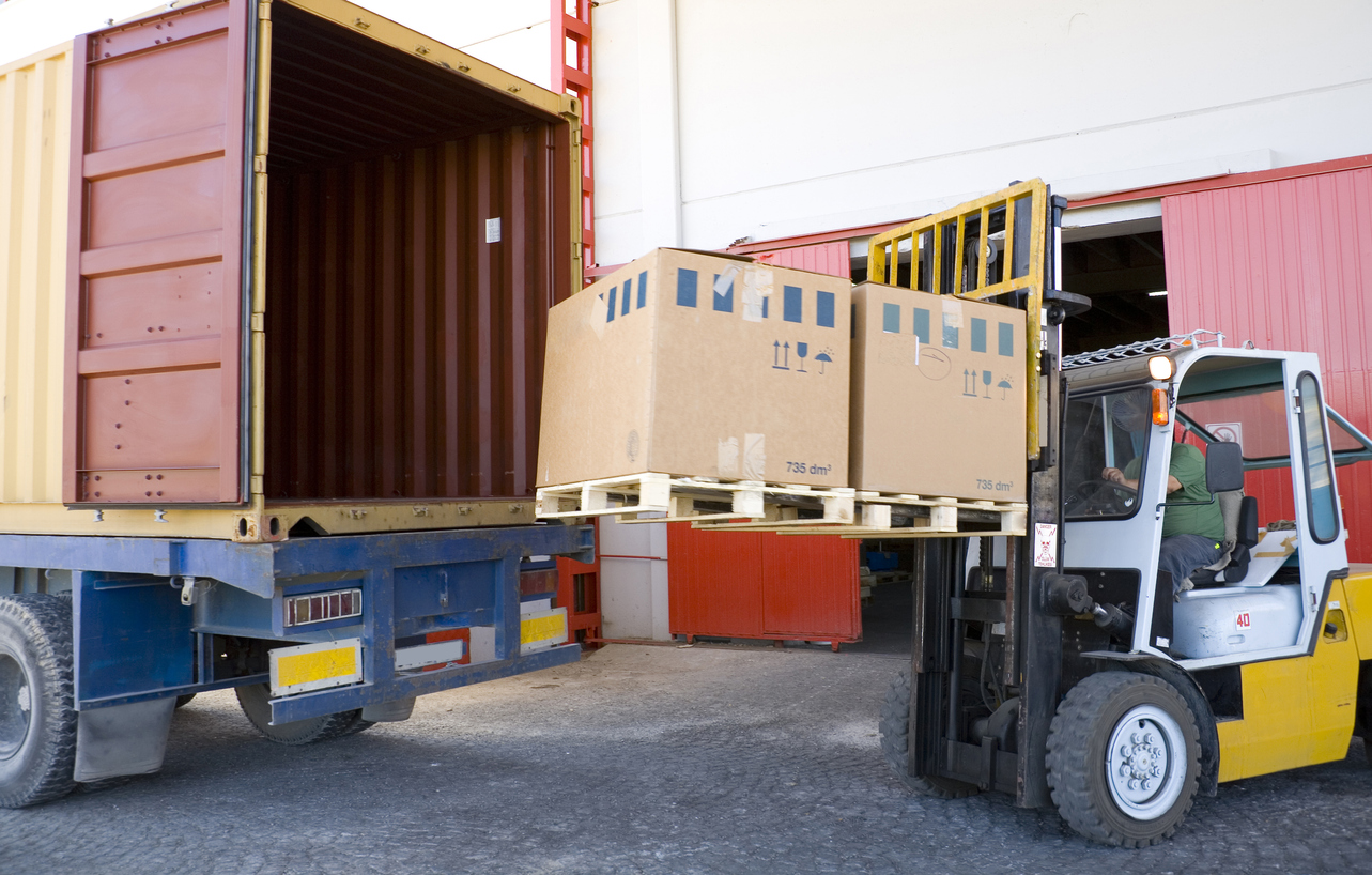 Forklift loading two pallets onto a truck