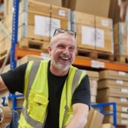Warehouse worker in a yellow safety vest taping a box