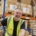 Warehouse worker in a yellow safety vest taping a box