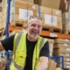 Warehouse worker in a yellow safety vest taping a box